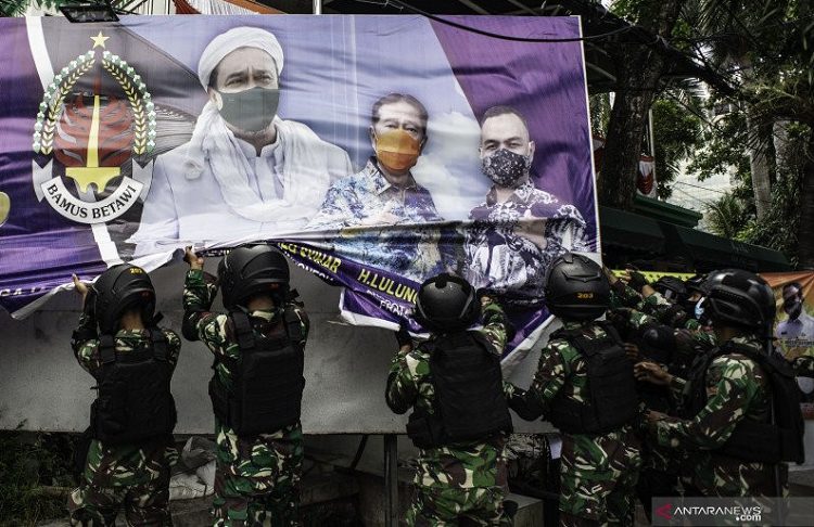 Anggota TNI menertibkan spanduk tidak berizin saat patroli keamanan di Petamburanm