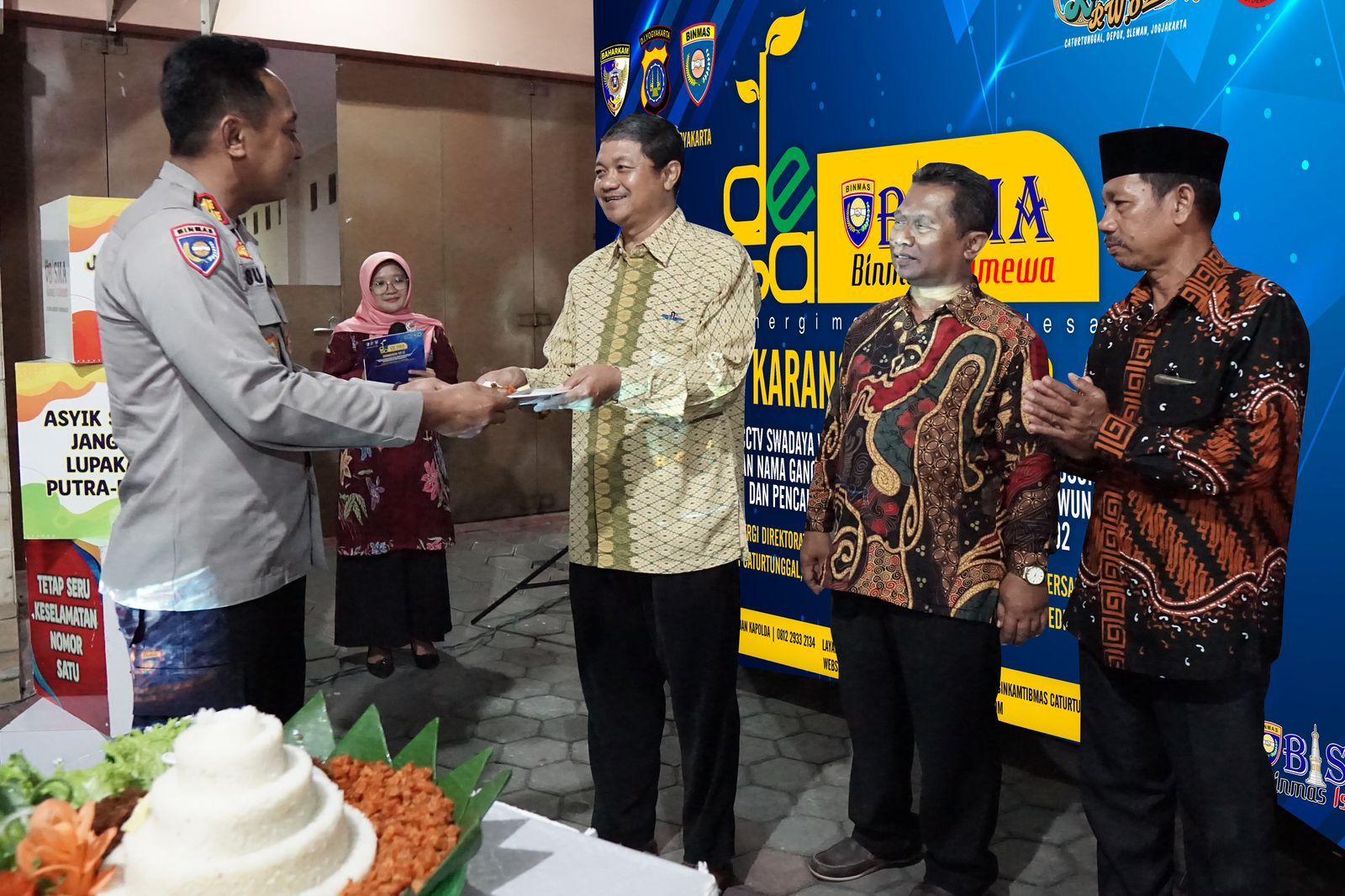 Wadirbinmas Polda DIY memberikan potongan tumpeng kepada Carik Caturtunggal saat pencanangan Desa Bisma.