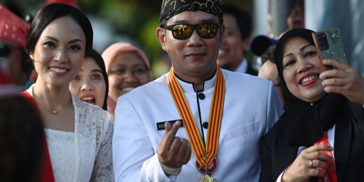 Gubernur Jawa Barat Ridwan Kamil berfoto bersama warga saat menghadiri Upacara Penurunan Bendera HUT ke-7