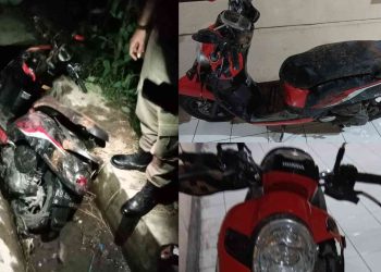 sepeda motor Scoopy warna merah hitam yang tertinggal di saluran irigasi di Ring Road Manding