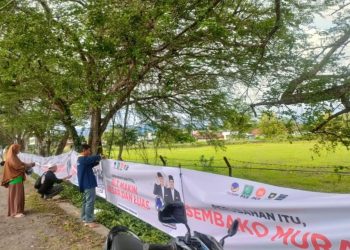 Relawan pasangan calon 01, Anies Baswedan dan Muhaimin Iskandar sedang memasang banner di Jalan Jogja - Wonosari, Kalurahan Gading, Playen