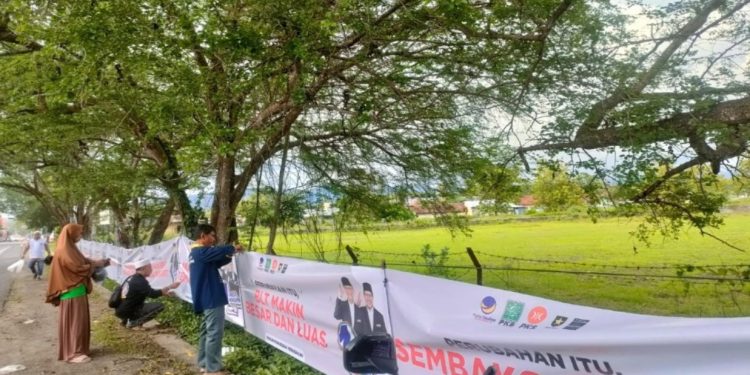 Relawan pasangan calon 01, Anies Baswedan dan Muhaimin Iskandar sedang memasang banner di Jalan Jogja - Wonosari, Kalurahan Gading, Playen