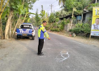 Seorang petugas kepolisian dari Unit Gakkum Polres Kulonprogo sedang melakukan olah TKP di lokasi kecelakaan maut yang terjadi di Jalan Wates-Sermo