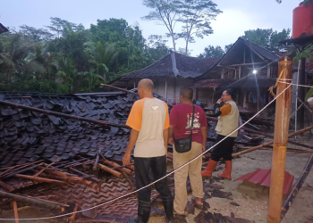 Petugas dan warga setempat memeriksa puing-puing rumah yang roboh akibat angin kencang di awal musim hujan