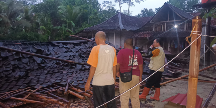 Petugas dan warga setempat memeriksa puing-puing rumah yang roboh akibat angin kencang di awal musim hujan