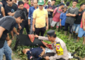 Anggota polisi bersama warga sekitar saat mengevakuasi jasad korban yang dìtemukan tewas penuh luka tusukan