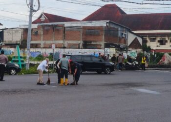 Petugas membersihkan lokasi kecelakaan di simpang empat Sagan, Caturtunggal, Depok, Sleman