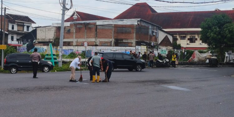 Petugas membersihkan lokasi kecelakaan di simpang empat Sagan, Caturtunggal, Depok, Sleman