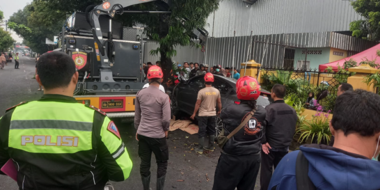 Polisi dan tim evakuasi mengangkat mobil yang menabrak dua motor dan pohon di Wiyoro, Banguntapan