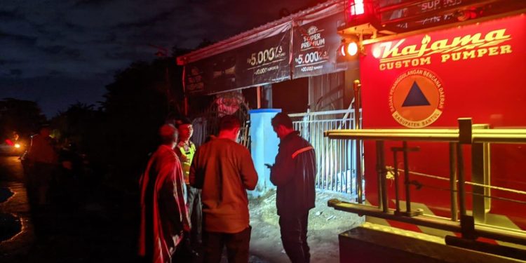 Petugas pemadam kebakaran bersama aparat kepolisian dan warga setempat berada di lokasi kebakaran warung kelontong milik Ibu Lastri di Padukuhan Ngablak, Sitimulyo, Piyungan, Bantul