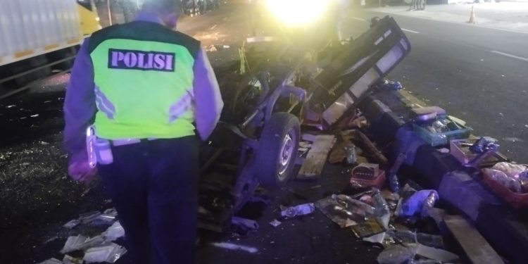 Seorang petugas kepolisian tengah melakukan olah TKP di lokasi kecelakaan lalu lintas yang melibatkan kendaraan bak terbuka di salah satu ruas jalan utama