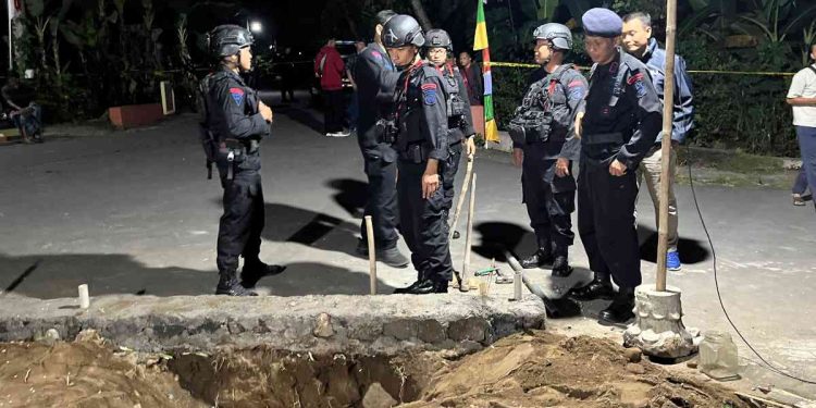 Petugas Jibom Gegana Brimob Polda DIY bersama Polsek setempat berjaga di lokasi penemuan benda diduga peluru mortir di Dusun Tanjung, Umbulmartani, Ngemplak, Sleman