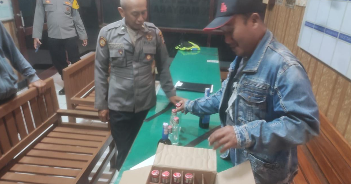 Petugas Polsek Kretek bersama warga menunjukkan puluhan botol minuman keras yang berhasil disita dalam razia penyakit masyarakat di wilayah Parangtritis, Bantul