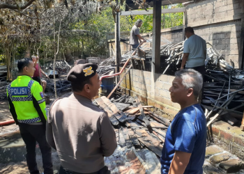 Petugas kepolisian bersama warga meninjau lokasi gudang perkakas yang terbakar di Dusun Gatak Klegung, Donokerto, Turi, Sleman