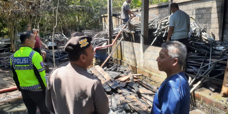 Petugas kepolisian bersama warga meninjau lokasi gudang perkakas yang terbakar di Dusun Gatak Klegung, Donokerto, Turi, Sleman