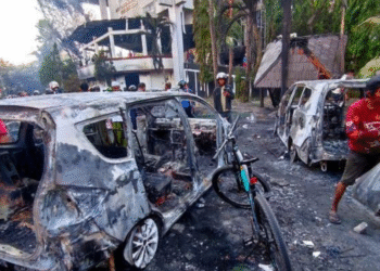 Sejumlah orang menbawa barang hasil jarahan usai Kantor DPRD Kota Makassar dibakar massa