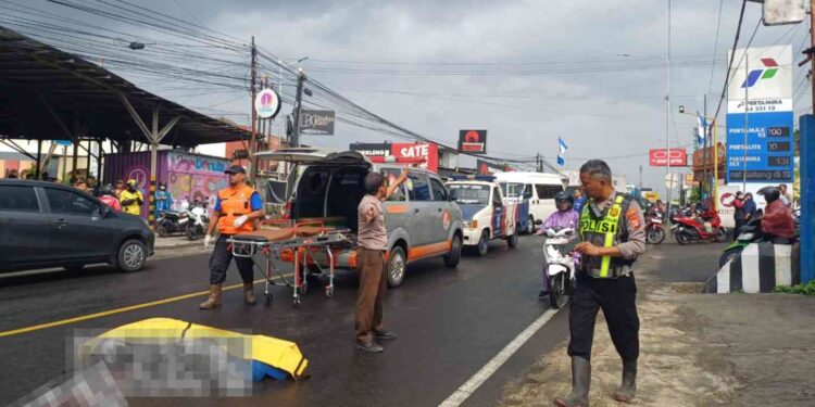 Petugas kepolisian bersama tim medis mengevakuasi korban kecelakaan lalu lintas di depan SPBU Mantub, Baturetno, Banguntapan, Bantul, Senin (15/9/2025). Seorang pengendara motor tewas di lokasi setelah terjatuh dan tertabrak truk boks.