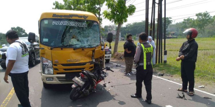 Petugas kepolisian bersama warga berada di lokasi kecelakaan antara sepeda motor Honda Revo dan kendaraan Isuzu ELF di Jalan Raya Yogya-Wates, Sedayu, Bantul, Minggu (21/9/2025).