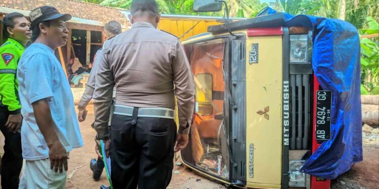 Petugas kepolisian bersama warga berada di lokasi kecelakaan truk Mitsubishi Colt Diesel bernomor polisi AB 8494 GC yang terguling di Jalan Wates–Sermo, Pengasih, Kulon Progo