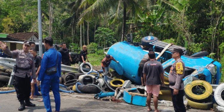 Petugas kepolisian bersama warga mengevakuasi truk tangki penyedot limbah yang terguling di Simpang Tiga Balong, Sermo Lor, Hargowilis, Kokap, Kulon Progo