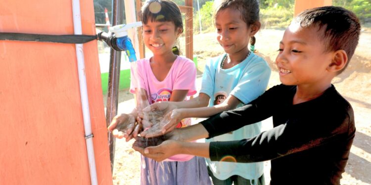 Anak- anak di Desa Kiuola, Kecamatan Noemuti, Kabupaten Timur Tengah Utara, menggunakan air bersih dari sumur bor sumber air bersih yang di bangun oleh BNPB, pada Kamis (28/8/2025)/ Dok. BNPB.