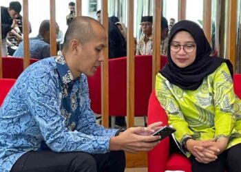 Bupati Banyuwangi, Ipuk Fiestiandani dan Principal Govtech Expert, Dewan Ekonomi Nasional (DEN), Rahmat Danu Andika, mencoba sistem perlinsos digital dengan Identitas Kependudukan Digital (IKD). (Foto: Muhammad Taufik Isnaini/KPM Kemkomdigi)