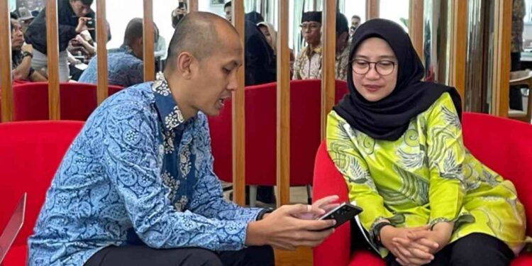 Bupati Banyuwangi, Ipuk Fiestiandani dan Principal Govtech Expert, Dewan Ekonomi Nasional (DEN), Rahmat Danu Andika, mencoba sistem perlinsos digital dengan Identitas Kependudukan Digital (IKD). (Foto: Muhammad Taufik Isnaini/KPM Kemkomdigi)