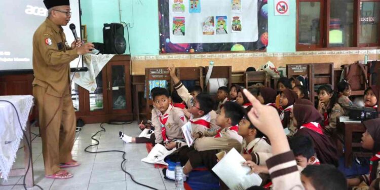 Frika Deddy Sofyan dari DLH Bojonegoro bersama Kepala SDN Kadipaten 1 Bojonegoro, Budiono memberi edukasi siswa tentang pengelolaan sampah