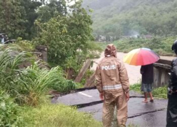 Petugas kepolisian dan warga meninjau jalan utama yang putus di Pedukuhan Wunut, Kalurahan Sriharjo, Imogiri, usai hujan lebat, Jumat (21/11/2025).