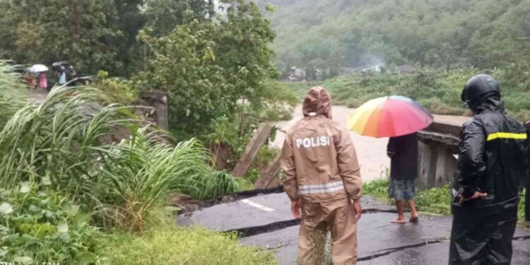 Petugas kepolisian dan warga meninjau jalan utama yang putus di Pedukuhan Wunut, Kalurahan Sriharjo, Imogiri, usai hujan lebat, Jumat (21/11/2025).