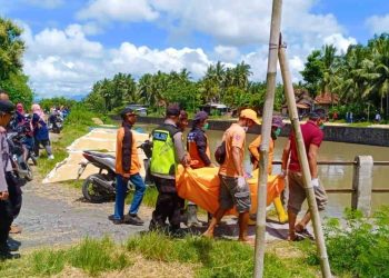 Petugas gabungan dari kepolisian, SAR, PMI, dan warga mengevakuasi jasad perempuan tanpa identitas yang ditemukan mengapung di Sungai Bedoyo, Karangsewu, Galur, Kulon Progo, Minggu (28/12/2025).