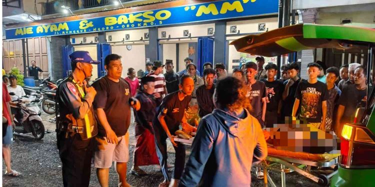 Petugas kepolisian bersama warga membantu proses evakuasi korban kecelakaan lalu lintas ke ambulans di kawasan Srimartani, Piyungan, Bantul, Minggu (11/1/2026) malam.