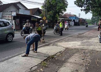 Petugas kepolisian bersama warga membersihkan sisa material di lokasi kecelakaan lalu lintas di Jalan Imogiri Timur, tepatnya di depan SMKN 1 Pleret, Bantul