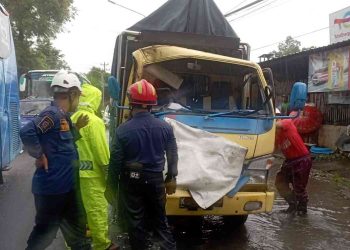 Petugas kepolisian dan relawan mengevakuasi truk engkel yang ringsek akibat kecelakaan beruntun di Jalan Parangtritis, Tembi, Sewon, Bantul, Minggu (11/1/2026). Insiden ini melibatkan tiga kendaraan dan menyebabkan satu pengemudi mengalami patah kaki serta beberapa penumpang luka ringan.