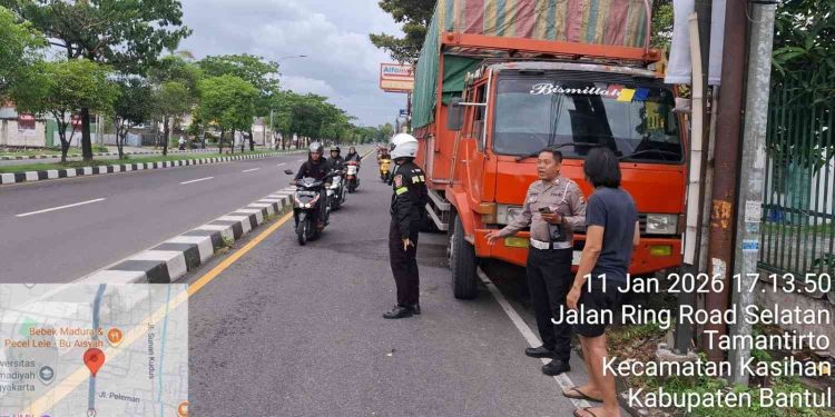Petugas kepolisian melakukan pengamanan dan pengaturan arus lalu lintas di lokasi kecelakaan yang melibatkan truk dan sepeda motor di Jalan Ring Road Selatan, Tamantirto, Kecamatan Kasihan, Kabupaten Bantul, Minggu (11/1/2026) sore.