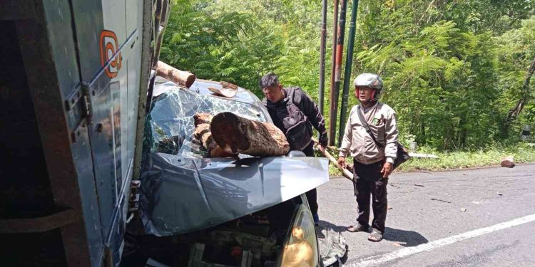 Petugas memeriksa kondisi mobil Grand Livina yang mengalami kerusakan parah pada bagian depan setelah tertimpa muatan kayu dari truk yang mundur di tanjakan Jalan Imogiri–Dlingo, Bantul, Kamis (7/1/2026).