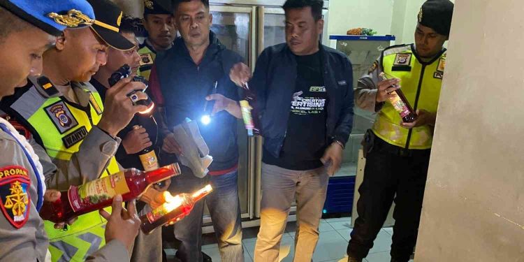 Petugas Sat Samapta Polres Bantul memeriksa dan mendata botol minuman keras ilegal yang disita saat penggerebekan di Outlet 23, Jalan Pasopati, Banguntapan, Bantul, Kamis (26/2/2026) malam. Operasi KRYD tersebut dilakukan sebagai tindak lanjut laporan masyarakat guna menekan peredaran miras tanpa izin dan menjaga situasi kamtibmas tetap kondusif.