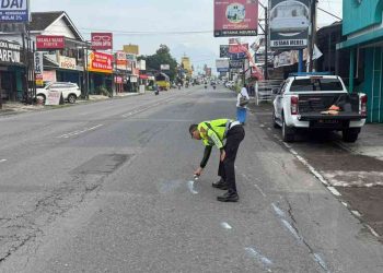 Petugas Satlantas Polresta Sleman melakukan olah tempat kejadian perkara dengan menandai titik benturan di Jalan Tajem, Maguwoharjo, Depok, Sleman, Sabtu (21/2/2026), usai kecelakaan tiga sepeda motor yang mengakibatkan satu pengendara meninggal dunia.