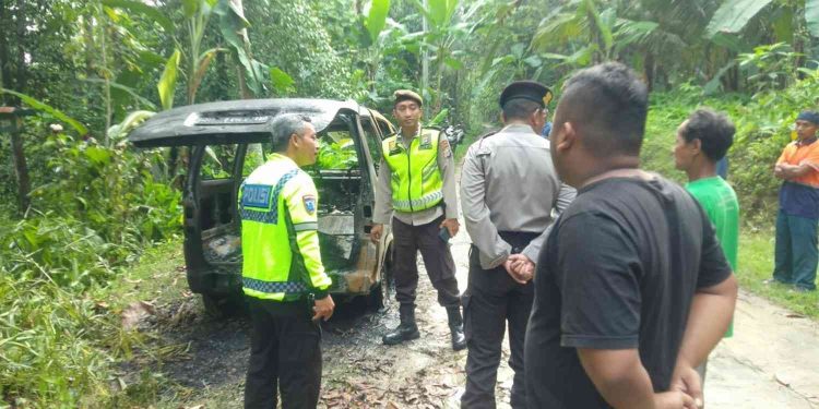 Petugas kepolisian bersama warga meninjau kondisi mobil Espas yang terbakar akibat dugaan korsleting listrik di jalan perkampungan Margosari, Pengasih, Kulon Progo, Kamis (19/2/2026). Tidak ada korban jiwa dalam peristiwa tersebut setelah api berhasil dipadamkan petugas pemadam kebakaran.