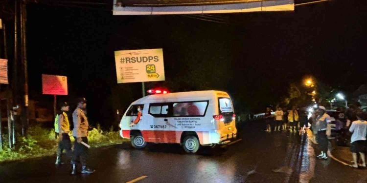 Petugas kepolisian melakukan olah tempat kejadian perkara (TKP) usai kecelakaan lalu lintas yang melibatkan dua sepeda motor dan satu mobil di Jalan Parangtritis, Dusun Paker, Mulyodadi, Bambanglipuro, Bantul, Minggu (15/2/2026) dini hari. Sebuah ambulans Palang Merah Indonesia tampak mengevakuasi korban, sementara arus lalu lintas di lokasi kejadian sempat terhenti.