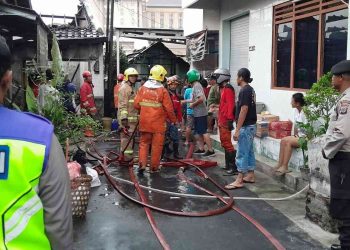 Petugas pemadam kebakaran bersama warga dan aparat kepolisian melakukan proses pendinginan serta penanganan pascakebakaran rumah di Padukuhan Blimbingsari, Caturtunggal, Depok, Sleman, Sabtu (21/2/2026).