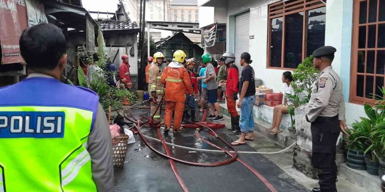 Petugas pemadam kebakaran bersama warga dan aparat kepolisian melakukan proses pendinginan serta penanganan pascakebakaran rumah di Padukuhan Blimbingsari, Caturtunggal, Depok, Sleman, Sabtu (21/2/2026).