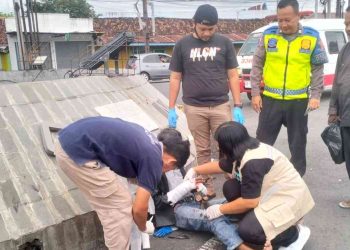 Petugas dan tenaga medis menangani pengendara Honda Vario yang terluka setelah terlibat kecelakaan dengan ambulans pembawa jenazah di Simpang Karangnongko, Wates, Kulon Progo, Sabtu (30/5/2026). Korban mengalami patah jari kelingking tangan kanan serta lecet pada tangan dan kaki. (Foto: Istimewa)