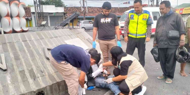 Petugas dan tenaga medis menangani pengendara Honda Vario yang terluka setelah terlibat kecelakaan dengan ambulans pembawa jenazah di Simpang Karangnongko, Wates, Kulon Progo, Sabtu (30/5/2026). Korban mengalami patah jari kelingking tangan kanan serta lecet pada tangan dan kaki. (Foto: Istimewa)