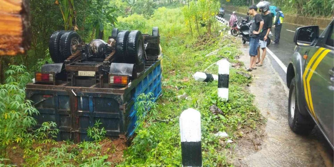 Truk Mitsubishi bernomor polisi H-9251-KE terbalik usai mengalami kecelakaan tunggal di Jalan Imogiri–Mangunan, tepatnya di kawasan tanjakan Song Be Susong, Giriloyo, Wukirsari, Imogiri, Bantul, Jumat (22/5/2026). Insiden terjadi saat hujan mengguyur wilayah tersebut, diduga akibat kendaraan selip hingga menghantam pembatas jalan dan terperosok ke sisi utara jalan. Pengemudi dilaporkan selamat tanpa mengalami luka.