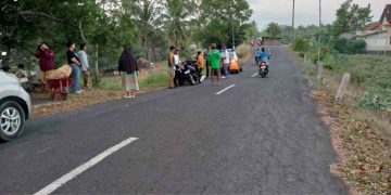 Caption gambar: Petugas dan warga berada di lokasi kecelakaan lalu lintas yang melibatkan sepeda motor Honda Beat dan seorang pejalan kaki di Jalan Pantai Glagah, Temon, Kulon Progo, Minggu (7/6/2026) pagi. Insiden terjadi saat korban pejalan kaki sedang mendorong gerobak angkong di tepi jalan dan tertabrak sepeda motor yang melaju searah dari belakang. Foto: Istimewa/Polres Kulon Progo.