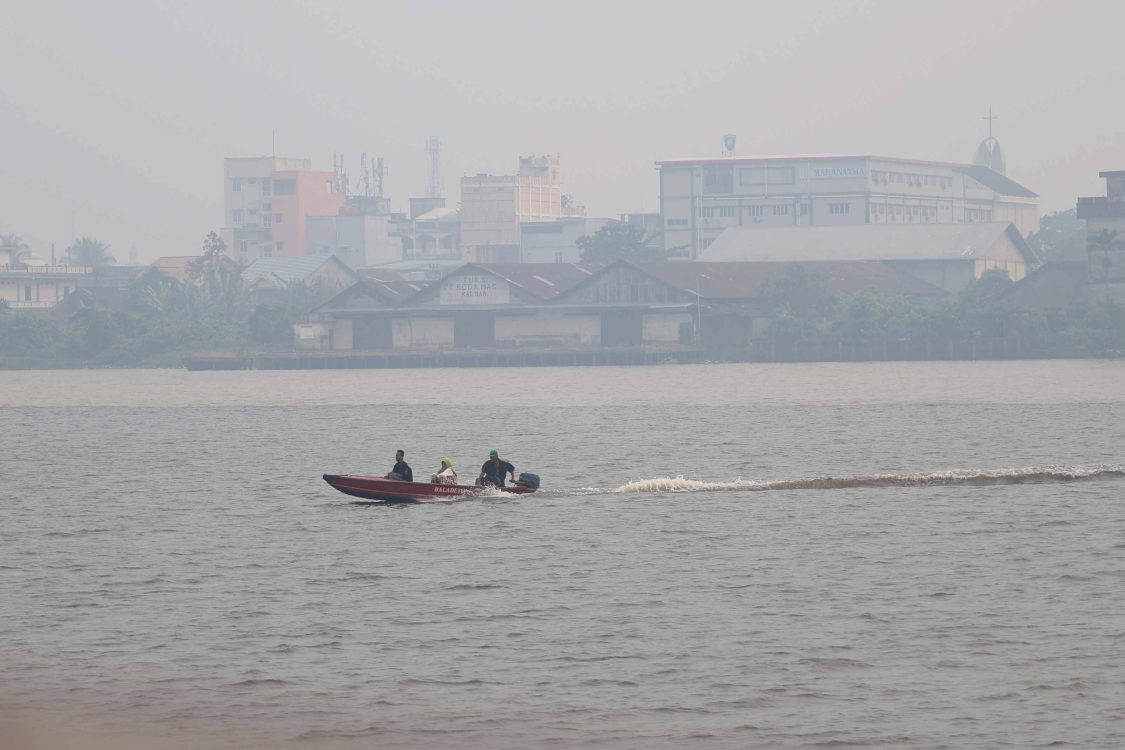 : Perahu motor bermuatan penumpang melintasi Sungai Kapuas yang diselimuti kabut asap di Pontianak, Kalimantan Barat, Minggu (23/8/2026). Menurut warga setempat yang menggunakan transportasi sungai, kabut asap akibat kebakaran hutan dan lahan (karhutla) yang menyelimuti wilayah tersebut menyebabkan jarak pandang di kawasan perairan yang sebelumnya luas menjadi terbatas hingga sekitar 20-30 meter. (ANTARA FOTO/Jessica Wuysang/wsj)