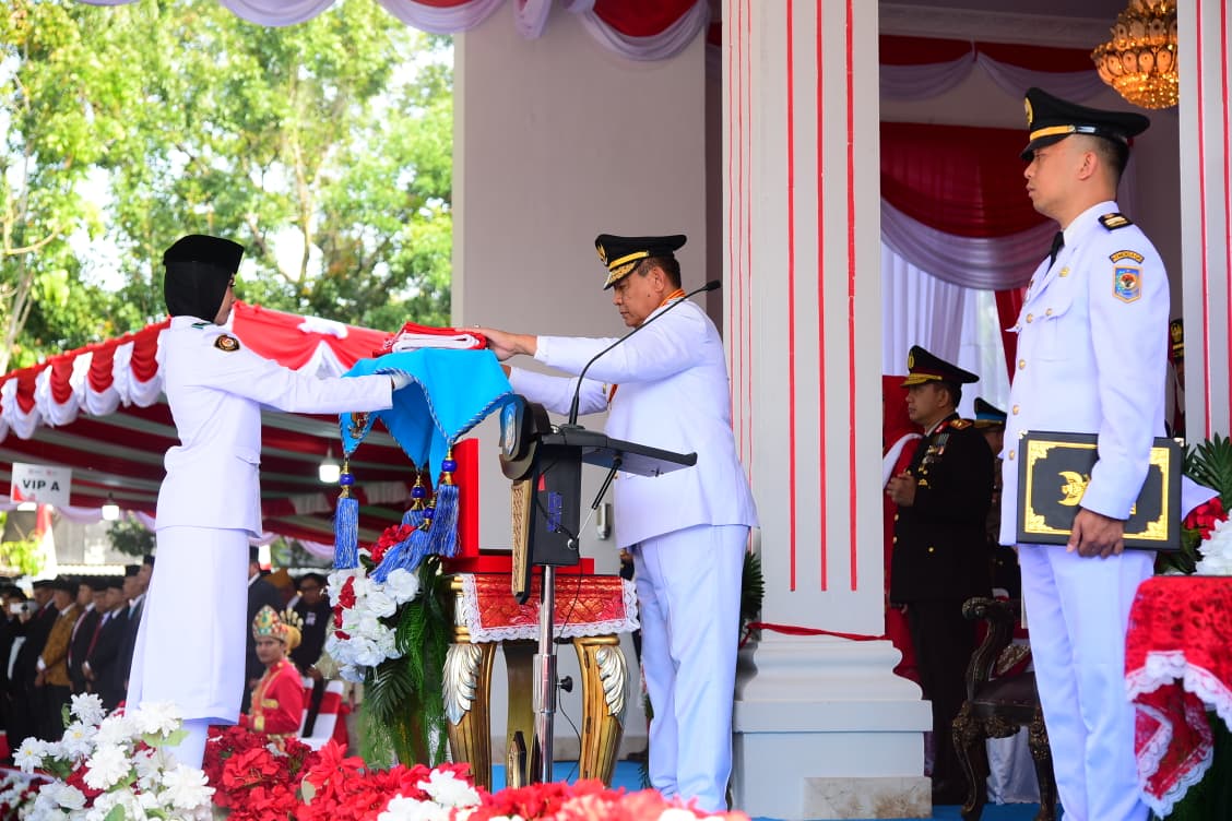 : Gubernur Gorontalo Gusnar Ismail saat menyerahkan bendera pusaka kepada petugas pembawa bendera saat pelaksanaan Upacara Hari Ulang Tahun (HUT) ke-81 Kemerdekaan Republik Indonesia tingkat Provinsi Gorontalo di halaman Rumah Jabatan Gubernur, Senin (17/8/2026). Foto – Nova Diskominfotik.