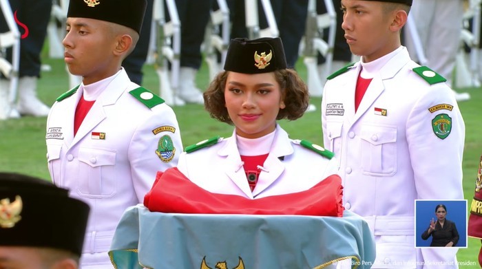 : Neeltje Deliana Insjowi Werimon berdiri dengan penuh kesiapan di antara barisan Pasukan Pengibar Bendera Pusaka (Paskibraka) Tim Indonesia Adil Makmur. Pelajar SMA Negeri 8 Jayapura, Papua, itu mendapat kepercayaan mengemban tugas paling penting dalam Upacara Penurunan Bendera Negara Sang Merah Putih di Istana Merdeka, Senin (17/8/2026). (Tangkapan Layar Setpres RI)