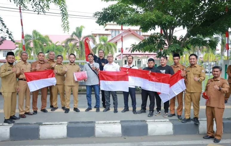 : Wakil Bupati Aceh Barat, Said Fadheil, menyerahkan bendera Merah Putih kepada perwakilan wartawan, dalam rangka memeriahkan Hari Ulang Tahun ke-81 Kemerdekaan Republik Indonesia. (Dok. Humas Pemkab Aceh Barat)